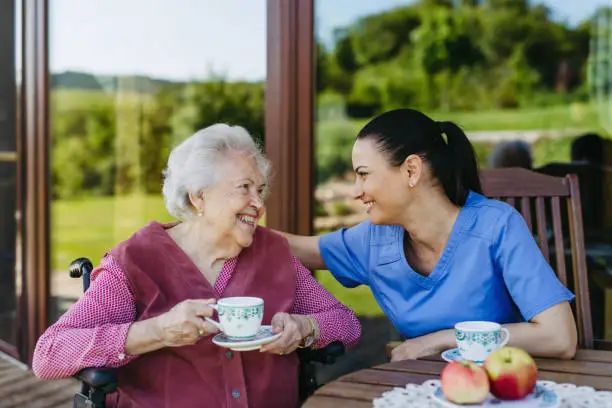 A carer sharing a cup of tea and a laugh with a resident