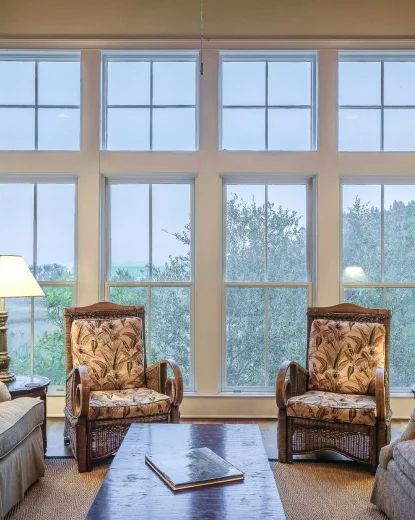 A bright sitting room with armchairs and garden windows